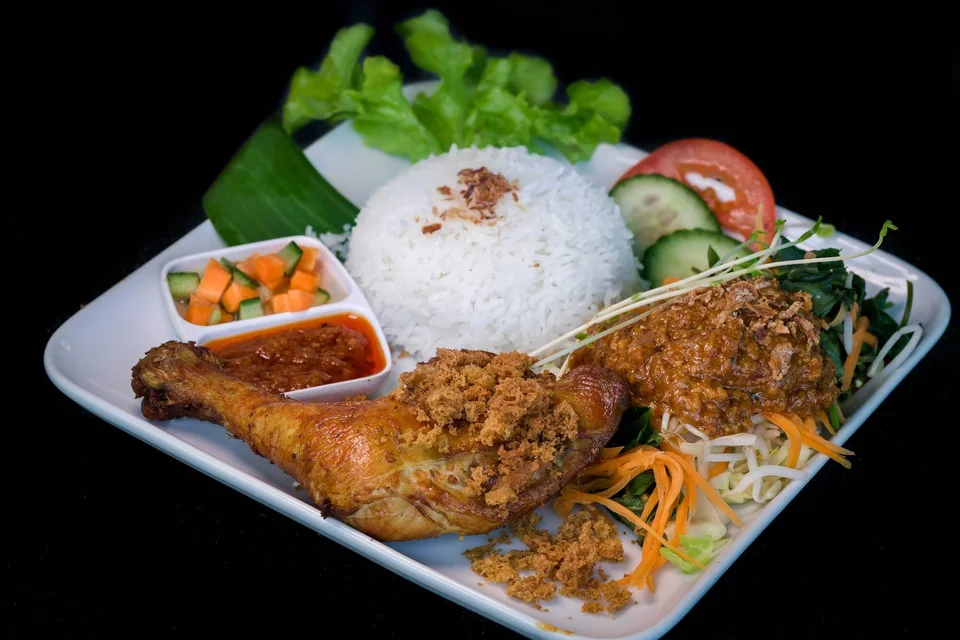 An Indonesian rice plate served with duck, vegetables and sambal